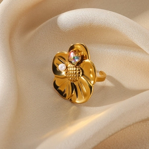 Detail of adjustable gold petal ring with a mini butterfly and white pearl on satin