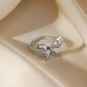 Detail of a polished silver bow ring with a clear zircon on champagne satin fabric