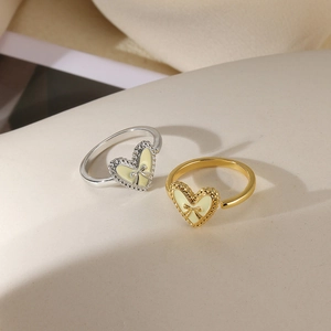 Detail of heart rings with yellow enamel and bow decoration on stone background
