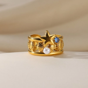 Macro detail of golden star ring with white pearl, blue zircon, and shell texture