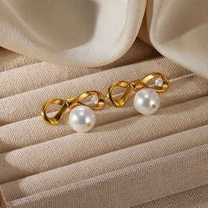Macro des boucles d'oreilles nœud plaquées or 18K avec perle blanche et zircon cœur