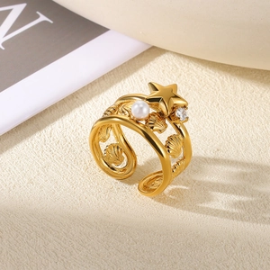 Detail of 18K gold ring with white pearl, starfish, and shell engraving on beige surface