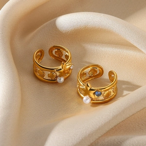 Golden star and shell open ring with white pearl and blue gemstone on satin background