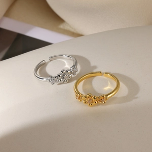Detail of adjustable open floral rings in gold and silver with zircon flower centers