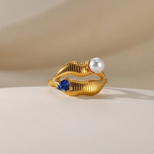 Detailed macro view of the gold-plated lip-shaped ring with pearl and blue heart gemstone