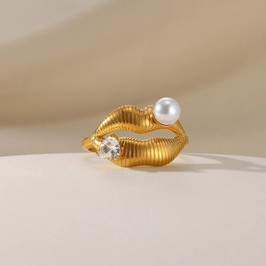 Detail of gold lip-shaped ring with white pearl and heart-shaped cubic zirconia stone