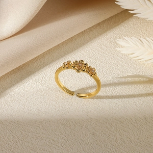 Detail shot of golden flower ring featuring three zircon stones on a silk fabric background