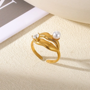Macro shot of gold open ring featuring pearl, heart zircon, and textured leaf detail