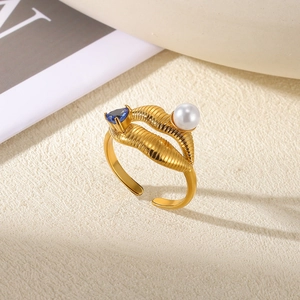 Detailed shot of a gold textured ring featuring a blue triangle gem and white pearl