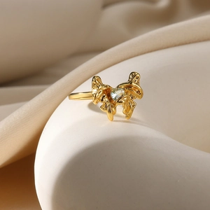 Macro shot of gold butterfly ring with heart-shaped gemstone on satin fabric