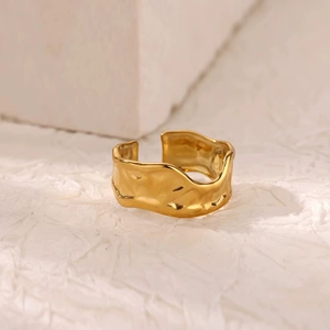 Macro detail of gold-plated stainless steel wide ring with irregular hammered texture