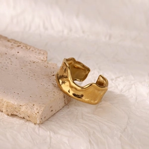 Detail of gold irregular wavy ring featuring modern lava texture on stone background