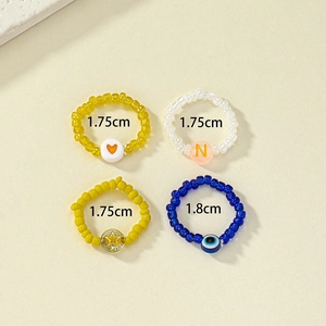 Detail of 4-piece handmade beaded rings featuring heart, star, and evil eye charms