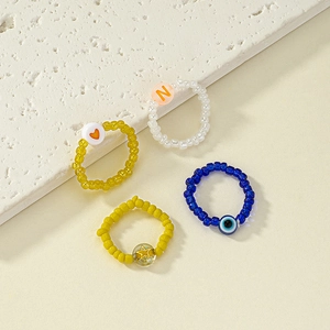 Minimalist beaded ring set with heart, star, evil eye, and letter N charms for women