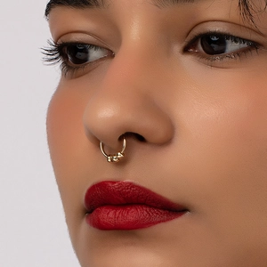 Detail of a polished gold non-pierced septum ring featuring three elegant small metal beads