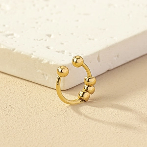 Macro shot of gold non-piercing beaded nose ring clip on textured stone background
