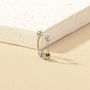 Macro view of silver clip-on nose ring featuring three sliding metal beads on a stone