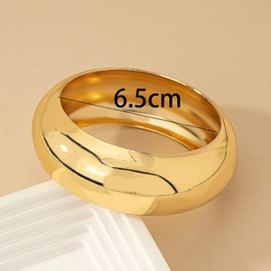 Close-up of wide polished gold bangle with 6.5cm inner diameter measurement