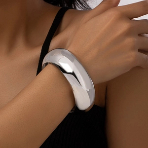 Close-up of a wide polished silver mirror metal bangle on a model's wrist