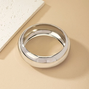 Top view of minimalist silver bangle with polished mirror finish on natural stone background