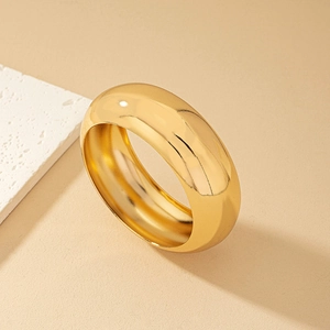 Close-up of minimalist gold-plated wide dome ring with polished mirror finish texture