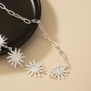 Silver sun pendant body chain jewelry with paperclip links on a textured background