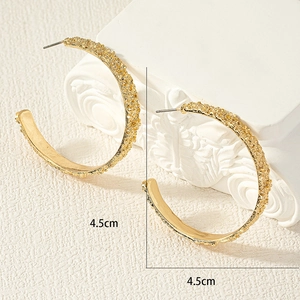 Detalle de pendientes C dorados de 4,5cm con textura de lava martillada y estilo vintage