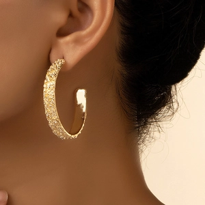 Pendientes de aro en C dorados con textura martillada mostrados en una modelo