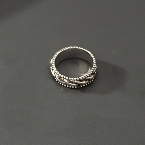 Detail eines Retro-Silberrings mit geflochtener Seiltextur und Perlenrand im Industriestil