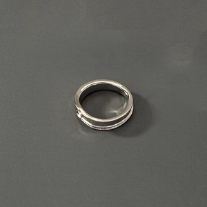 Makroaufnahme eines silbernen polierten Metallrings mit zentraler Rille und industrieller Textur