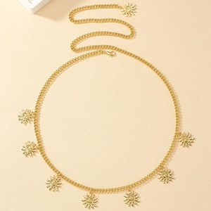 Macro detail of golden metal waist chain featuring embossed sun pendants with face designs