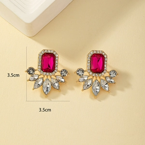 Dettaglio di orecchini vintage dorati con grandi cristalli rosso rosa e strass lucidi