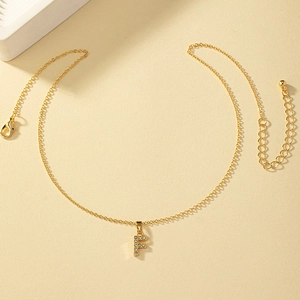 Dettaglio della collana dorata con lettera F in strass e chiusura a moschettone regolabile