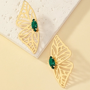 Detail of hollow butterfly earrings with marquise-cut green gemstone in gold finish