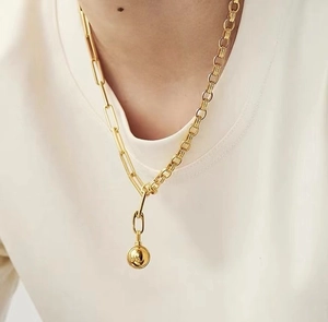 Detail of 18K gold-plated asymmetrical paperclip chain necklace with round ball pendant
