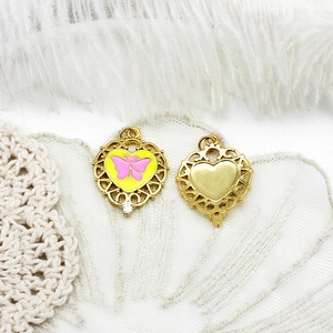 Detail view of heart-shaped gold pendant with pink butterfly pattern and small zircon stone