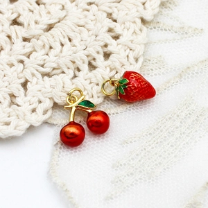 Vue macro de breloques fraise et cerise en émail plaqué or 18K pour la création de bijoux DIY