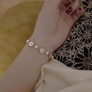 Détail du bracelet fleur en or 18 carats avec perles blanches et nacre pour femme