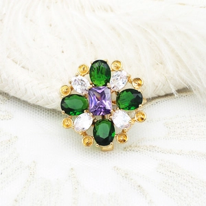Nahaufnahme einer Vintage-Goldbrosche mit Smaragd- und lila Steinen auf Spitze