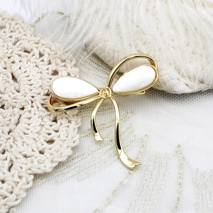 Broche nœud élégante plaquée or 18 carats avec nacre naturelle sur fond de dentelle blanche
