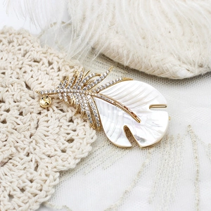 Broche plume élégante dorée 18K avec nacre naturelle et incrustations de cristaux