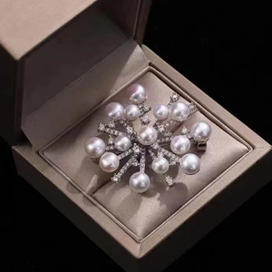 Macro shot of luxury pearl snowflake brooch with zircon pavé in a beige silk gift box