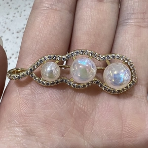 Macro view of gold pea pod brooch with three white pearls and pavé set micro diamonds