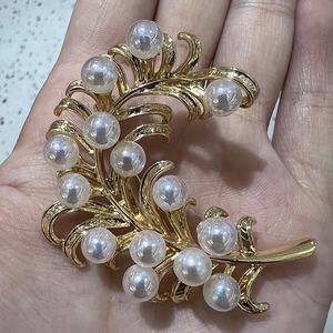 Detail of gold ice cream feather brooch with white faux pearls and fine silk texture