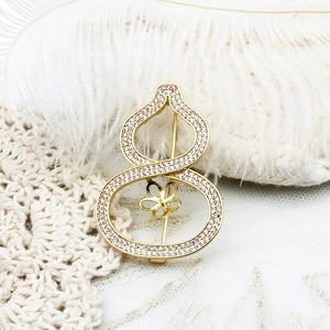 Elegant gold gourd brooch with white zircon pavé on white feather and lace background