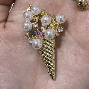 Macro shot of gold ice cream brooch featuring faux pearls and colorful gemstones