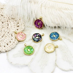 Detail view of colorful mosaic shell pendants with golden Fatima hand on white lace