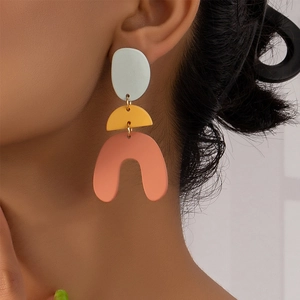 Geometric tiered drop earrings featuring colorful pastel shapes on a female model