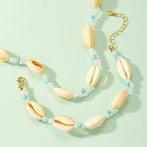 Bohemian style shell and bead necklace with gold clasp on mint green background