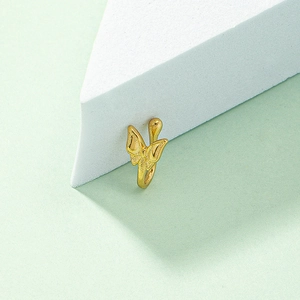 Detailed close-up of golden butterfly non-pierced nose ring on a white marble background